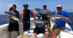 Five men on fishing charter holding 6 large fish.